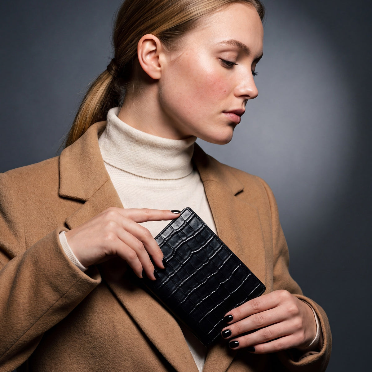 Woman sliding a black crocodile-embossed leather passport holder by GENTCREATE into a coat pocket