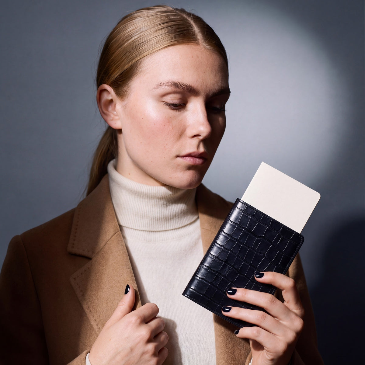 Woman holding a black crocodile-embossed leather passport holder by GENTCREATE with a blank card tucked in