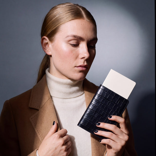 Woman holding a black crocodile-embossed leather passport holder by GENTCREATE with a blank card tucked in