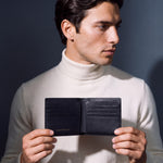 Man opening a black lizard-embossed leather bifold wallet by GENTCREATE to show the card slots