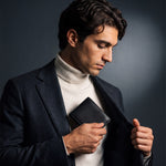 Man sliding a black lizard-embossed leather bifold wallet by GENTCREATE into a blazer pocket