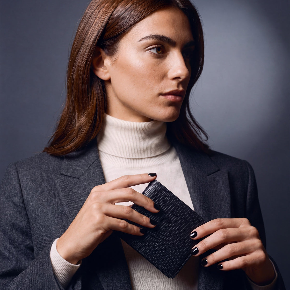 Woman sliding a black lizard-embossed leather bifold wallet by GENTCREATE into a blazer pocket