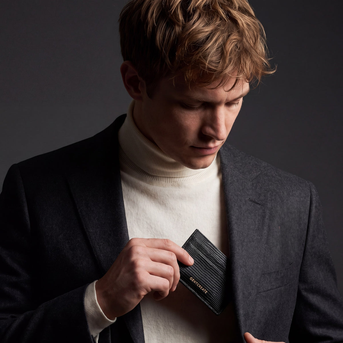 Man slipping a black lizard-embossed leather card holder by GENTCREATE into a blazer chest pocket