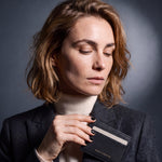 Woman slipping a black lizard-embossed leather card holder by GENTCREATE into a blazer chest pocket