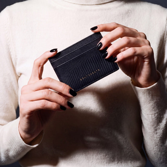 Hands holding a black lizard-embossed leather card holder by GENTCREATE, close-up
