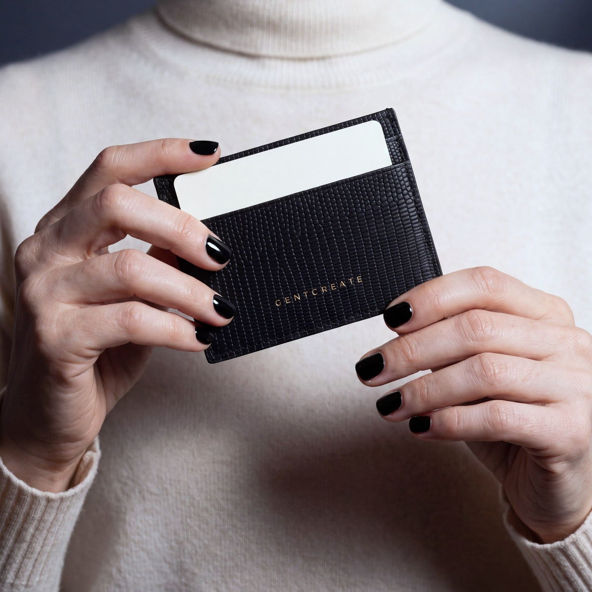 Hands holding a black lizard-embossed leather card holder by GENTCREATE, close-up