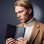 Man opening a black lizard-embossed leather passport holder by GENTCREATE with a passport inside