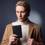 Man holding a black lizard-embossed leather passport holder by GENTCREATE with a blank card tucked in