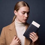 Woman holding a black lizard-embossed leather passport holder by GENTCREATE with a blank card tucked in