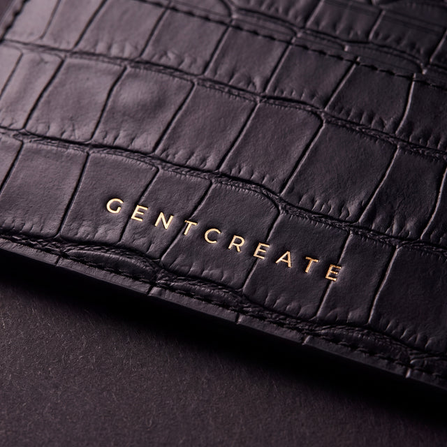 Κοντινό πλάνο της χρυσής σφραγίδας GENTCREATE σε μαύρη καρτοθήκη από ματ δέρμα με ανάγλυφο κροκό