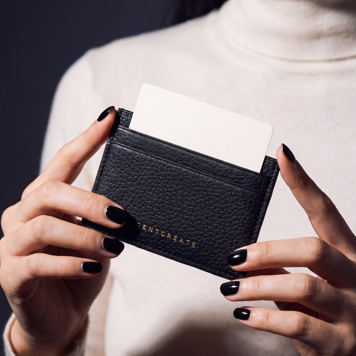 Close-up of hands holding a black pebble leather card holder by GENTCREATE with a card in the top slot