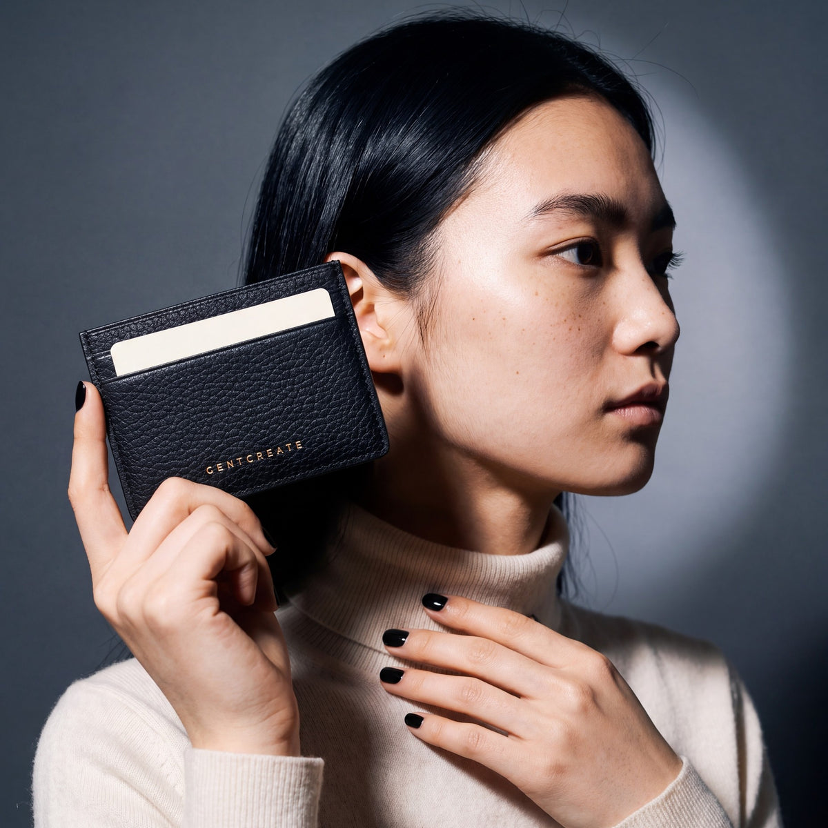 Woman holding a slim black pebble leather card holder by GENTCREATE between two fingers