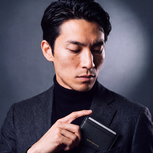 Man slipping a black pebble leather card holder by GENTCREATE into a blazer chest pocket