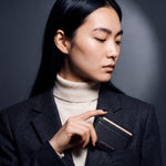 Woman slipping a black pebble leather card holder by GENTCREATE into a blazer chest pocket