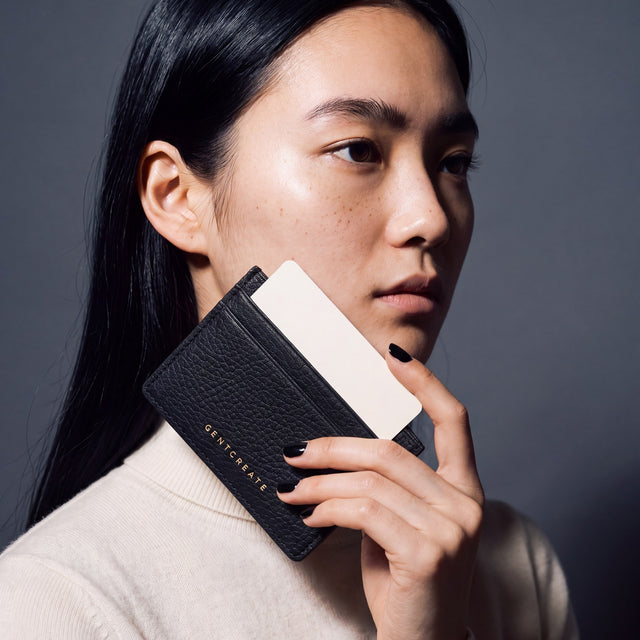 Woman holding a slim black pebble leather card holder by GENTCREATE and drawing out a card