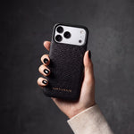 Hand with black nails holding a black pebble-grain calfskin iPhone 18 Pro Max case by GENTCREATE