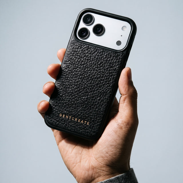Hand holding a black pebble-grain leather iPhone 18 Pro Max case by GENTCREATE against pale grey