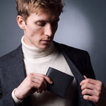 Man sliding a black Saffiano leather bifold wallet by GENTCREATE into a blazer pocket