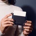 Close-up of hands holding a black Saffiano leather card holder by GENTCREATE with a card in the top slot