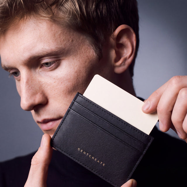 Man holding a slim black Saffiano leather card holder by GENTCREATE and drawing out a card