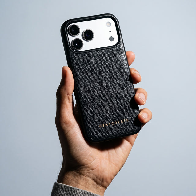 Hand holding a black Saffiano cross-hatch calfskin iPhone 18 Pro Max case by GENTCREATE against pale grey