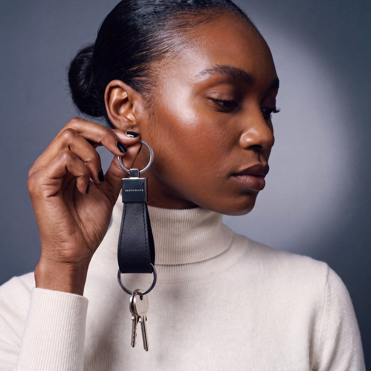 Woman holding a black Saffiano leather keychain by GENTCREATE up beside the face