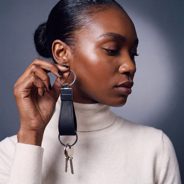 Woman holding a black Saffiano leather keychain by GENTCREATE up beside the face