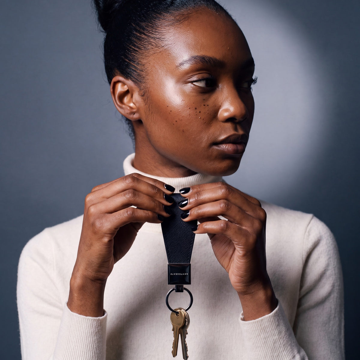 Woman holding up a black Saffiano leather keychain by GENTCREATE with house keys