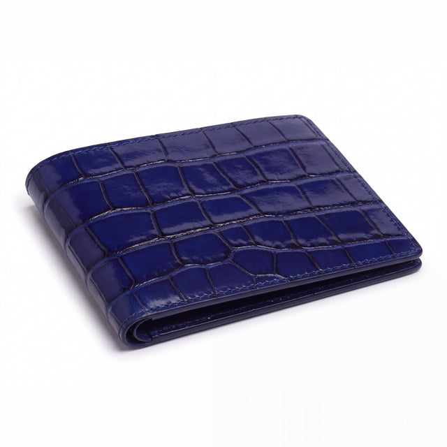 Closed blue glossy crocodile-embossed leather bifold wallet by GENTCREATE lying on white