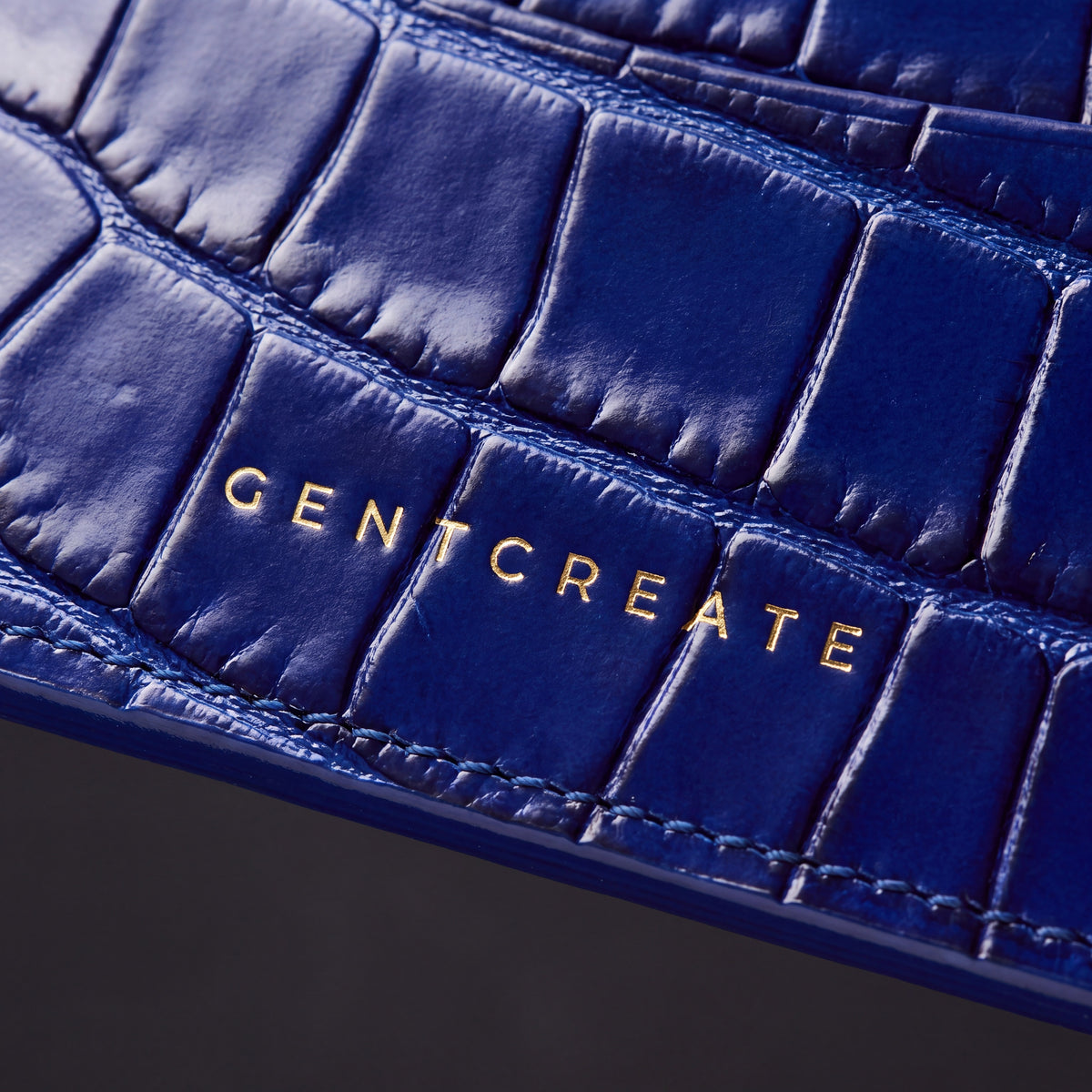 蓝色亮面鳄鱼纹压花皮革卡包上的烫金 GENTCREATE 标志特写