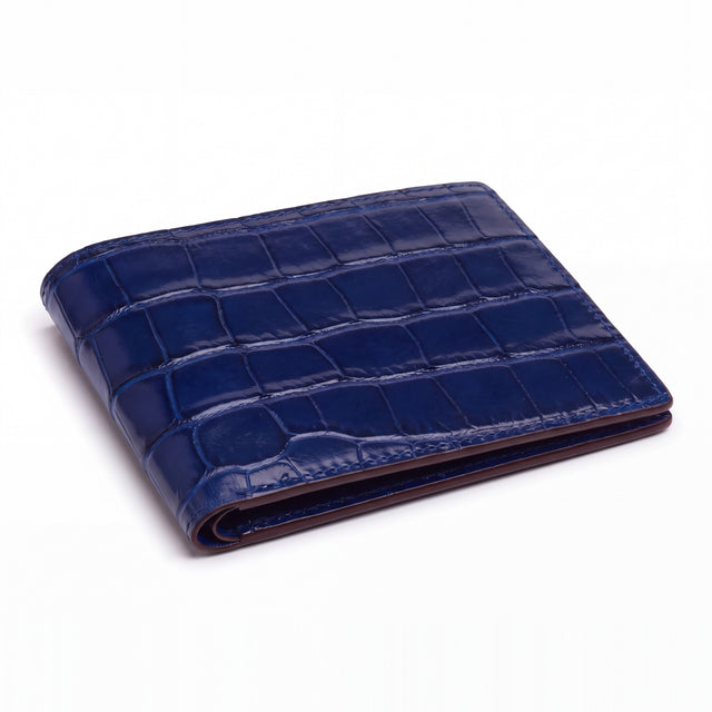 Closed blue matte crocodile-embossed leather bifold wallet by GENTCREATE lying on white