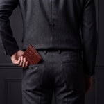 Man sliding a brown crocodile-embossed leather bifold wallet by GENTCREATE into his back trouser pocket