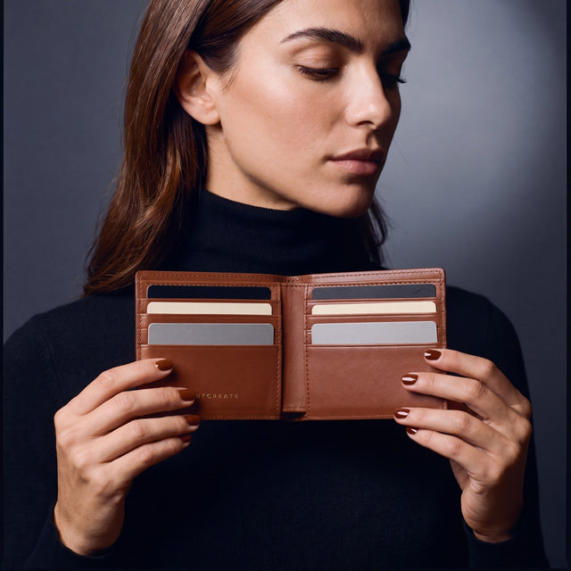 Woman opening a brown crocodile-embossed leather bifold wallet by GENTCREATE to show the card slots