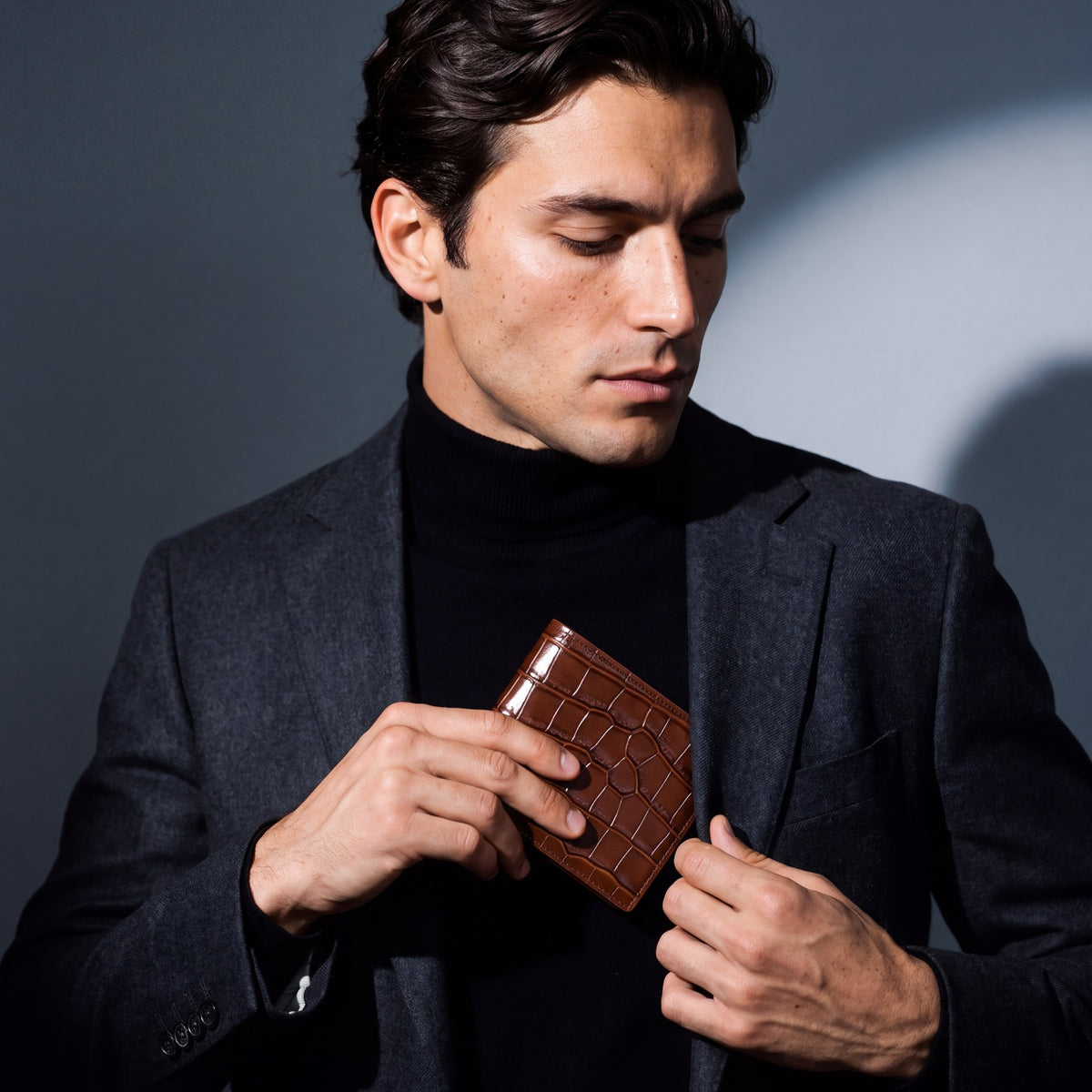 Man sliding a brown crocodile-embossed leather bifold wallet by GENTCREATE into a blazer pocket