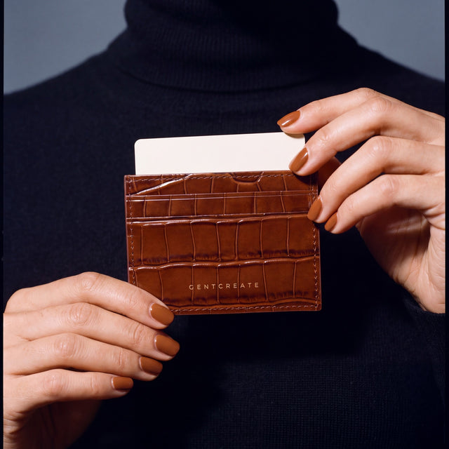 Close-up of hands holding a brown crocodile-embossed leather card holder by GENTCREATE with a card in the top slot