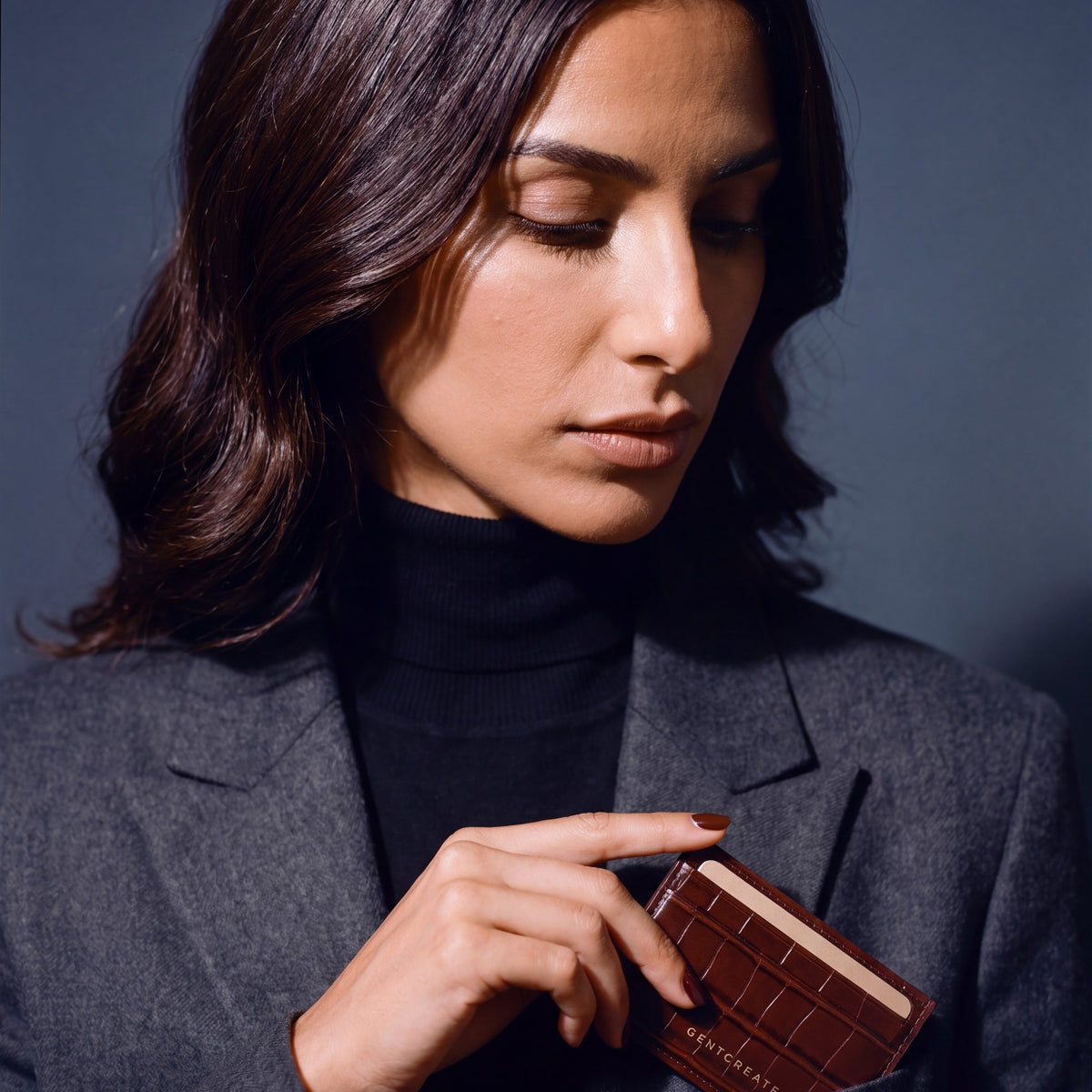 Woman slipping a brown crocodile-embossed leather card holder by GENTCREATE into a blazer chest pocket