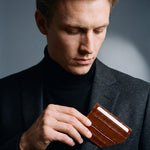 Man slipping a brown crocodile-embossed leather card holder by GENTCREATE into a blazer chest pocket