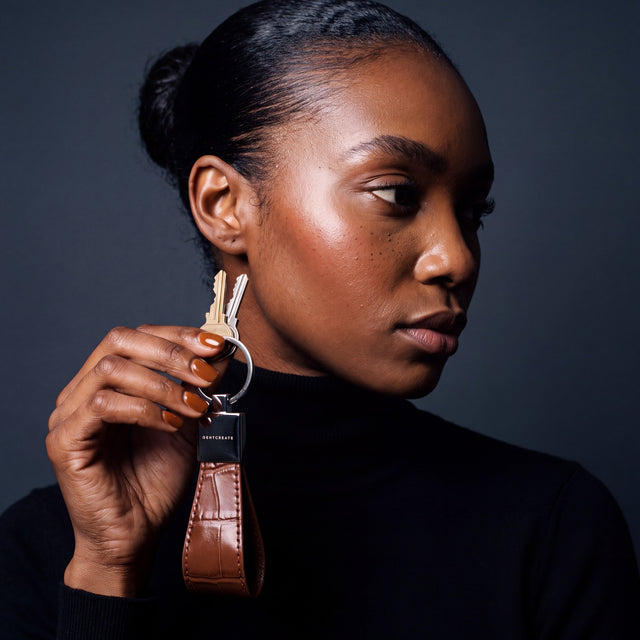 Woman holding up a brown crocodile-embossed leather keychain by GENTCREATE with house keys