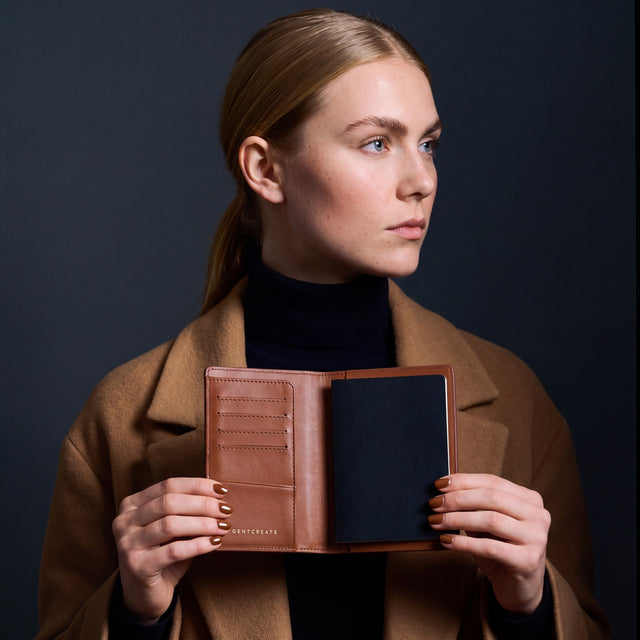 Woman opening a brown crocodile-embossed leather passport holder by GENTCREATE with a passport inside