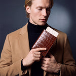 Man holding a brown crocodile-embossed leather passport holder by GENTCREATE with a blank card tucked in