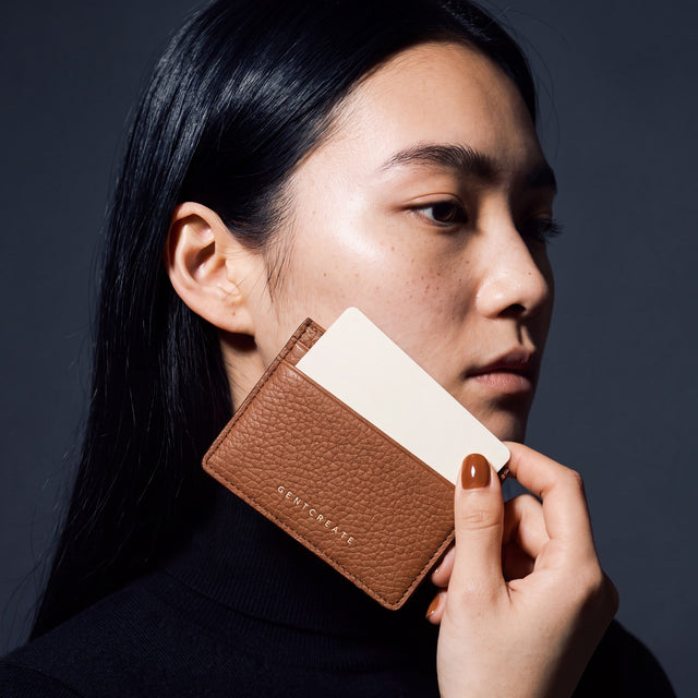 Woman holding a slim brown pebble leather card holder by GENTCREATE and drawing out a card