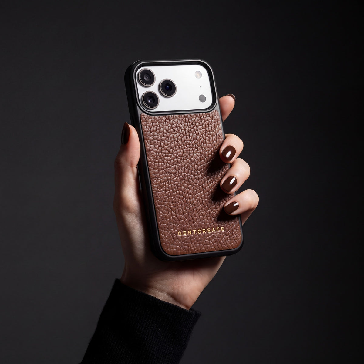 Hand with chocolate-brown nails holding a brown pebble-grain calfskin iPhone 18 Pro Max case by GENTCREATE
