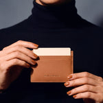 Hands holding a brown Saffiano leather card holder by GENTCREATE, close-up