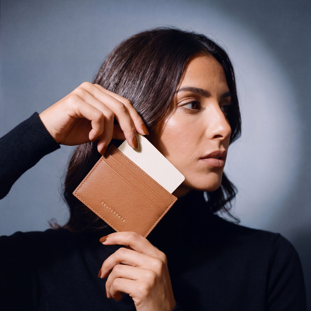 Woman holding a slim brown Saffiano leather card holder by GENTCREATE and drawing out a card