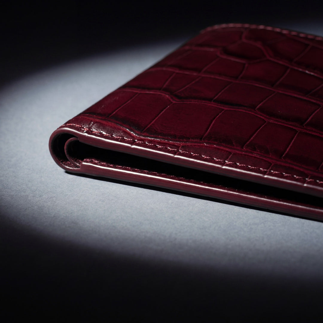 Close-up of the painted edge and stitching of a burgundy crocodile-embossed GENTCREATE wallet