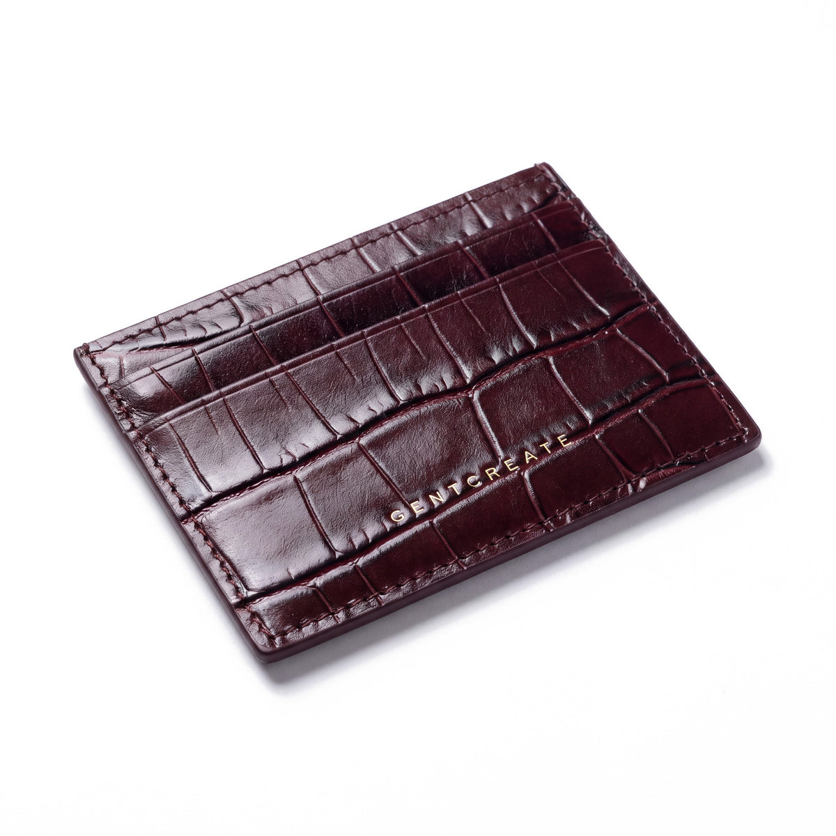 Burgundy crocodile-embossed leather card holder by GENTCREATE lying at an angle on white