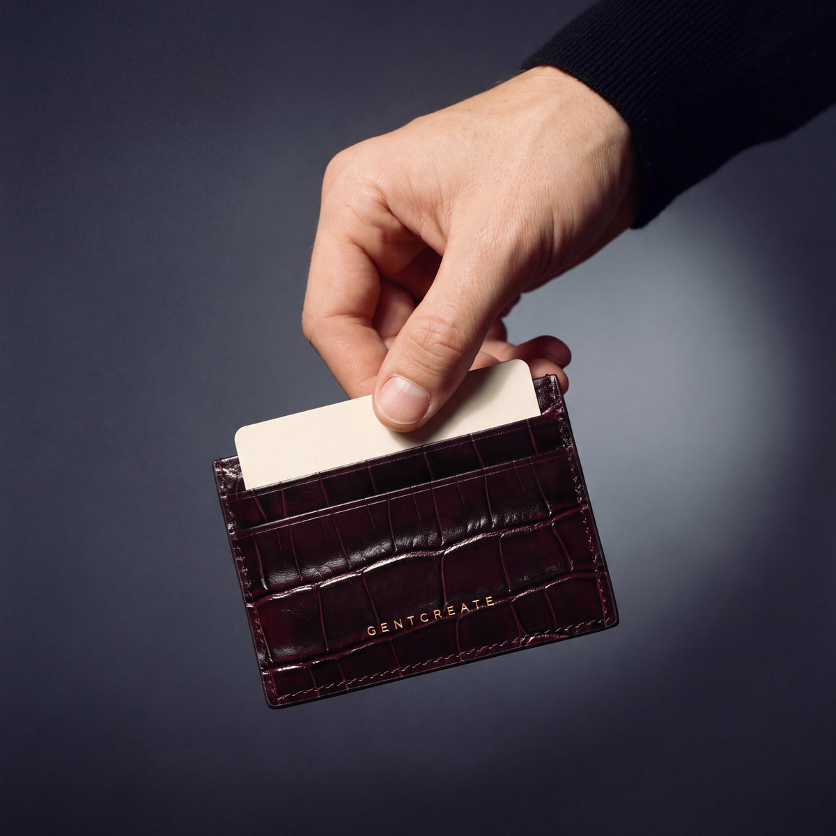 Hand holding a burgundy crocodile-embossed leather card holder by GENTCREATE, a card rising from the top slot
