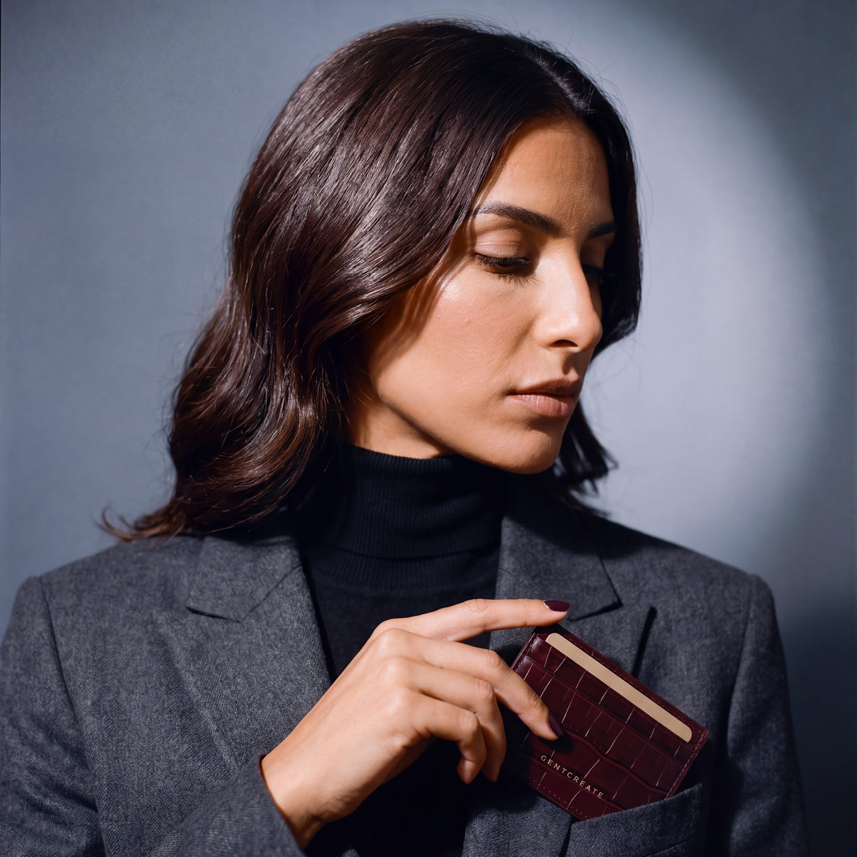 Woman slipping a burgundy crocodile-embossed leather card holder by GENTCREATE into a blazer chest pocket