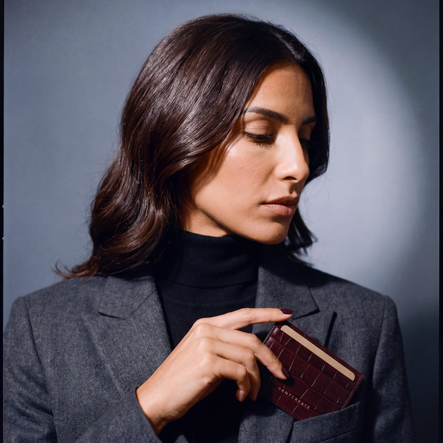 Woman slipping a burgundy crocodile-embossed leather card holder by GENTCREATE into a blazer chest pocket