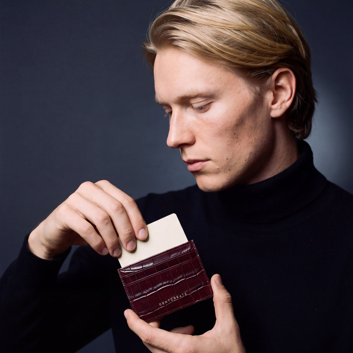 Man sliding a card into a burgundy crocodile-embossed leather card holder by GENTCREATE